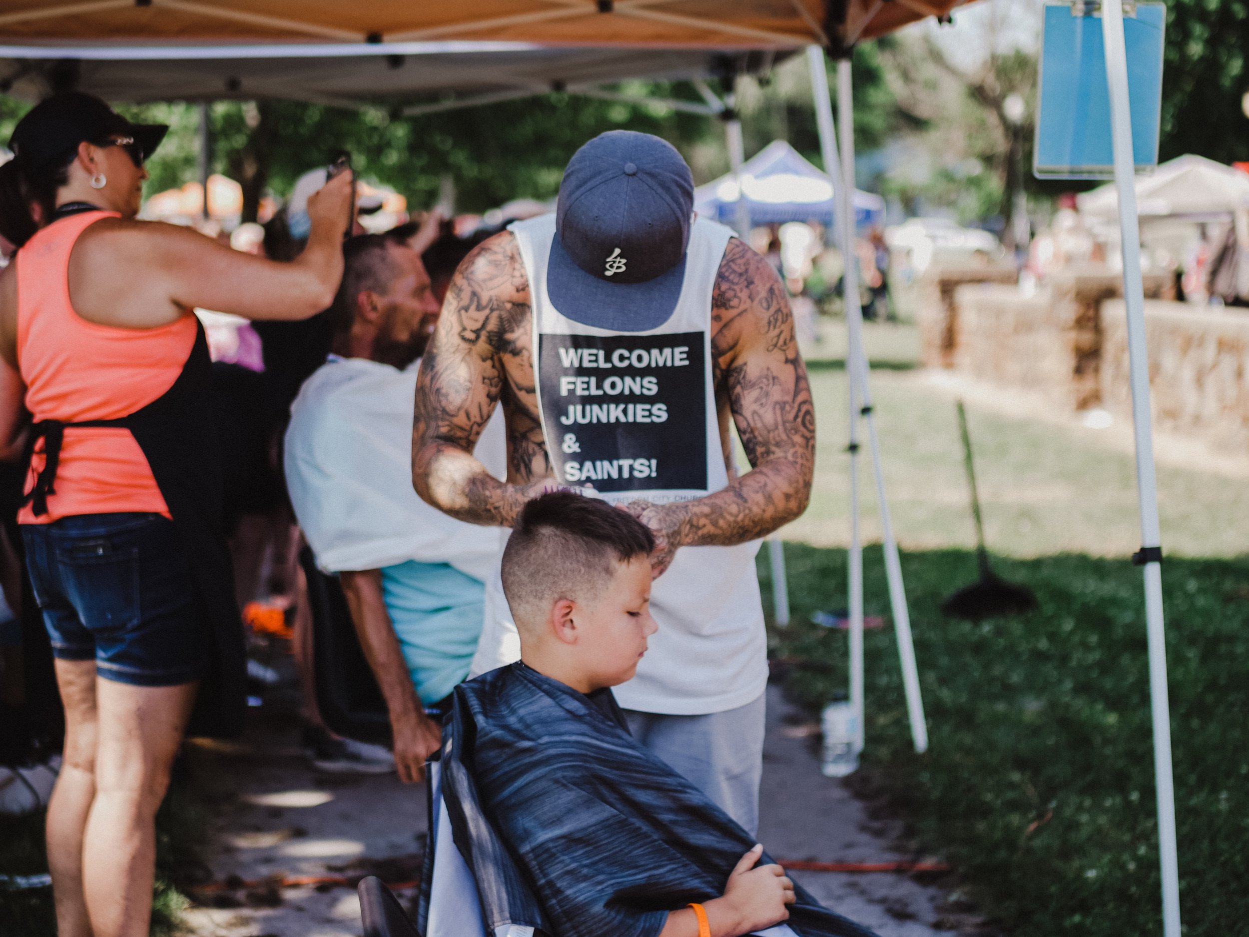 Straight Street resident volunteering at a community outreach event by providing free haircuts.